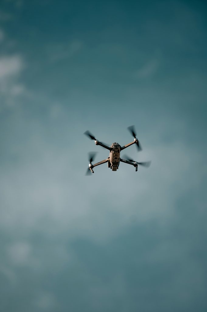 A quadcopter drone flies against a clear blue sky with slightly blurred rotors, evoking a sense of freedom and modern technology in action.