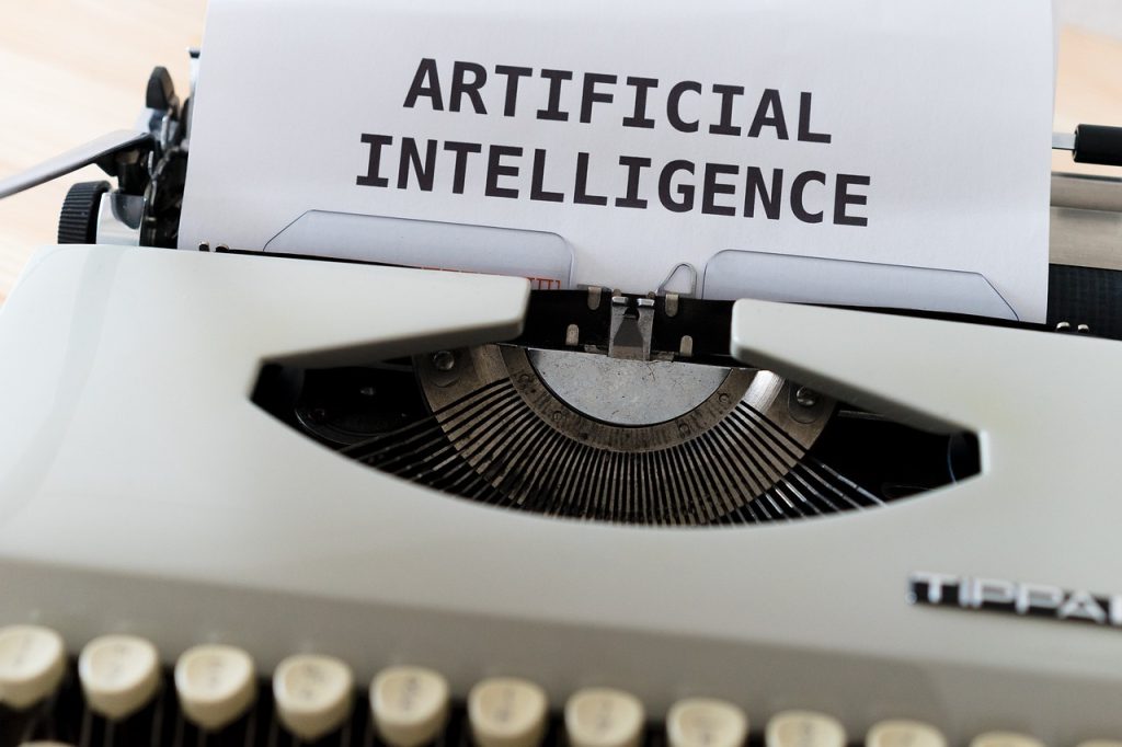 Close-up of a vintage typewriter with a paper displaying "ARTIFICIAL INTELLIGENCE" in bold letters, conveying a blend of tradition and technology.